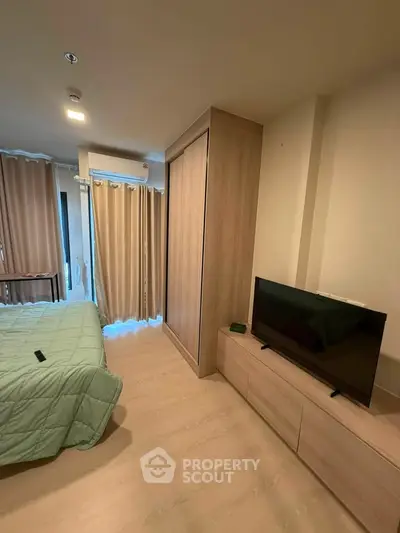 Modern bedroom with wooden flooring, TV, and large wardrobe in a cozy apartment.