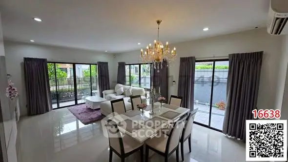 Spacious modern living room with elegant chandelier and large windows opening to a garden view.