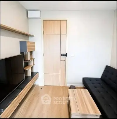 Modern living room with sleek furniture and wall-mounted TV in a cozy apartment.