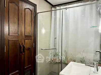 Elegant bathroom with glass shower and wooden door, perfect for modern living.