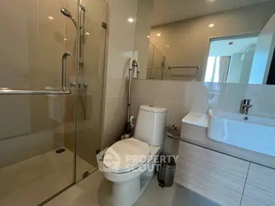 Modern bathroom with glass shower enclosure, sleek vanity unit, and well-placed lighting creating a bright and inviting space.