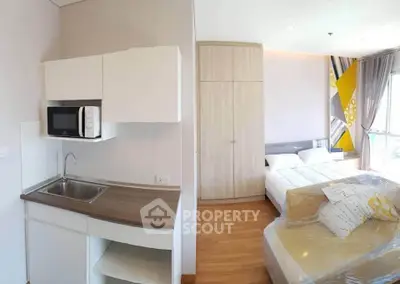 Modern studio apartment with compact kitchen and cozy bedroom area, featuring stylish decor and natural light.