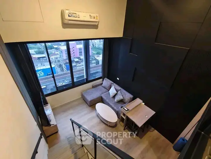 Modern loft-style living room with large windows and city view, featuring cozy seating and sleek design.