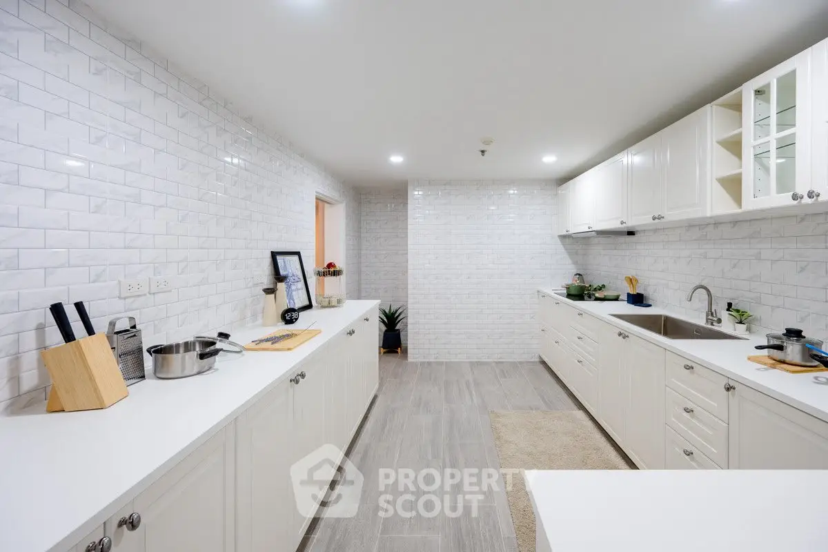 Spacious modern kitchen with sleek white cabinetry and elegant tile backsplash.