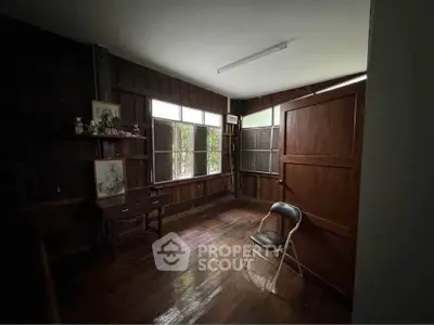 Cozy rustic room with wooden walls and natural light, perfect for a study or creative space.