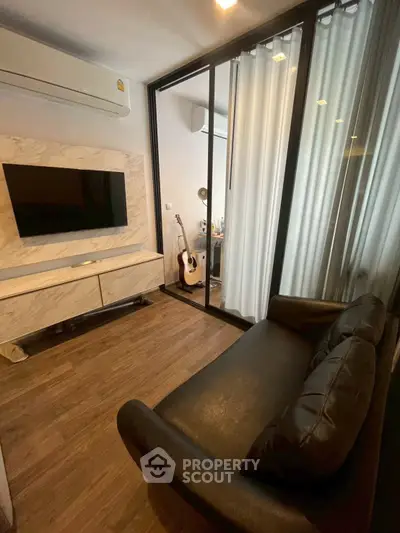 Modern living room with sleek design, featuring a black leather sofa, wall-mounted TV, and wooden flooring.