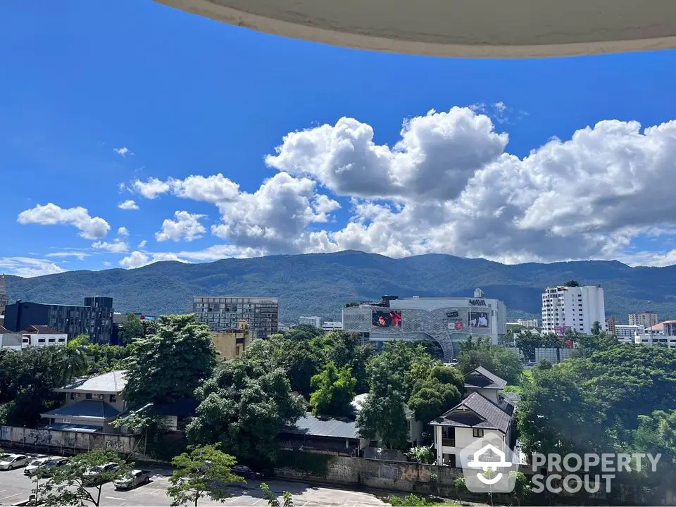 Stunning cityscape view with lush greenery and mountains under a clear blue sky.