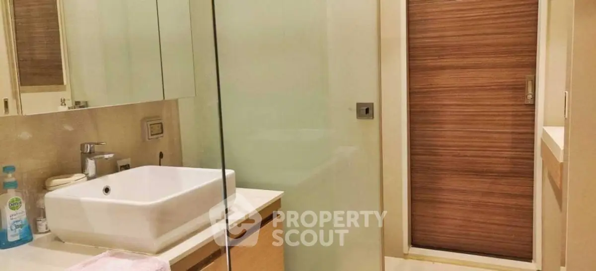 Modern bathroom with glass shower and sleek wooden accents