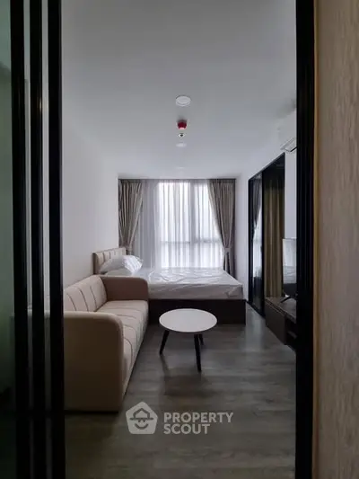 Modern bedroom with cozy sofa and natural light, perfect for relaxation.