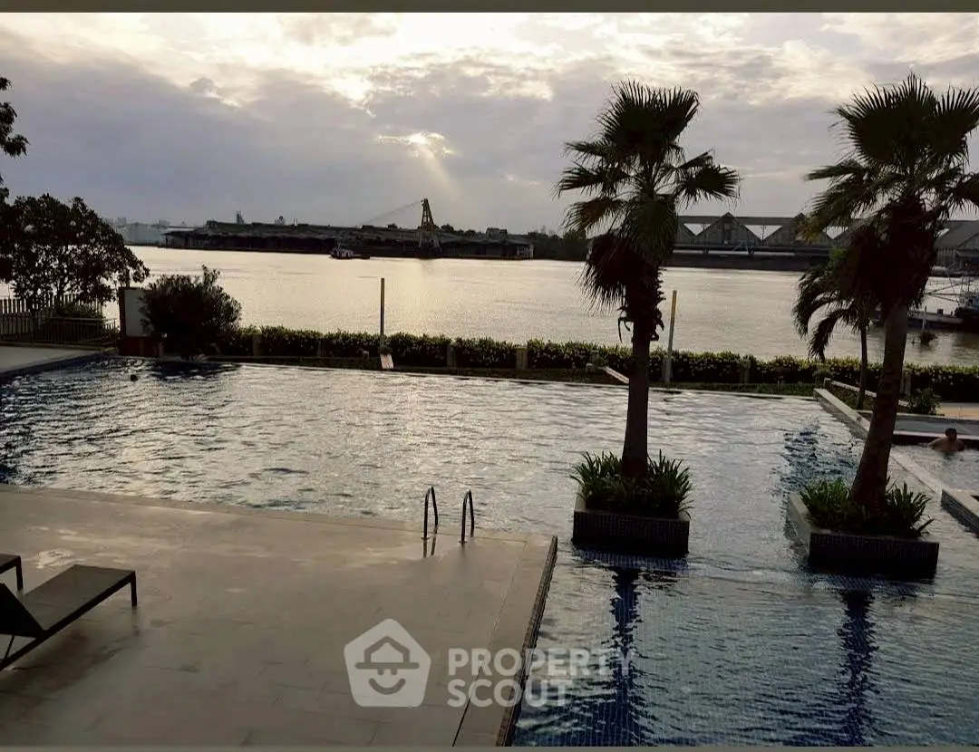 Luxurious riverside pool with stunning sunset view and palm trees, perfect for relaxation and leisure.