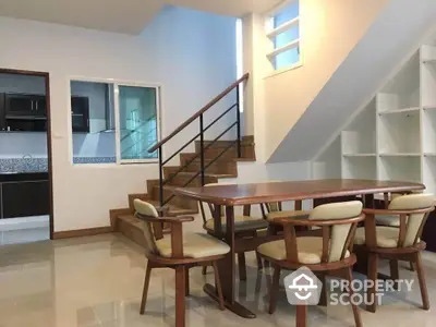 Modern dining area with wooden table and chairs near staircase in open-plan home