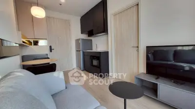 Modern living room with sleek kitchen and cozy seating area in stylish apartment.