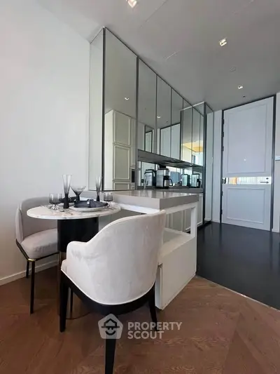 Modern kitchen with sleek design and open layout, featuring elegant dining area and mirrored cabinets.