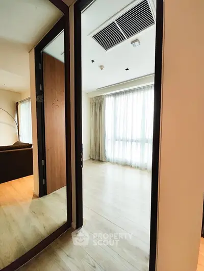 Spacious modern living room with wooden flooring and large windows for natural light.
