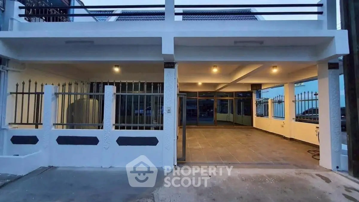 Modern two-story building exterior with spacious covered parking area and stylish lighting.