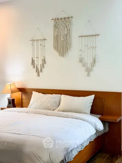 Cozy bedroom with wooden bed frame and elegant wall hangings, perfect for relaxation.