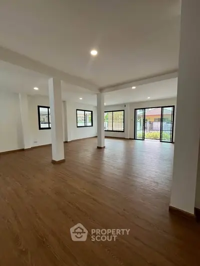 Spacious open-plan living room with large windows and wooden flooring