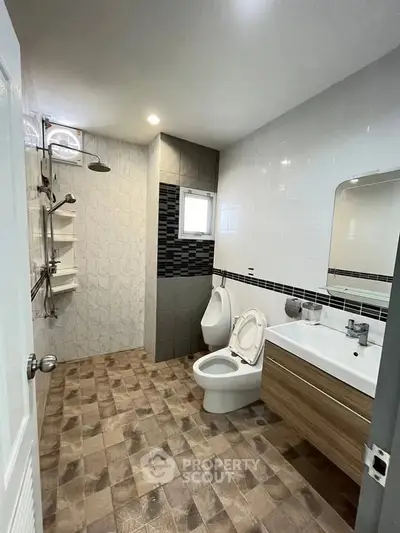 Modern bathroom with sleek fixtures and stylish tile flooring, featuring a spacious shower area and contemporary vanity.