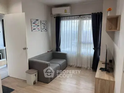Cozy living room with modern decor, featuring a comfortable sofa, wall-mounted TV, and natural light from large windows.