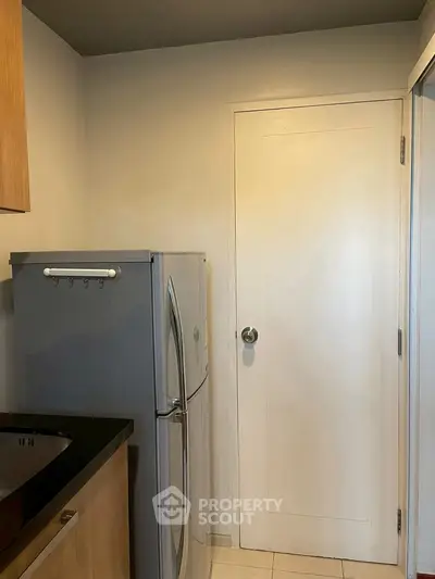 Compact kitchen area with modern fridge and sleek cabinetry