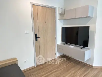 Modern living room with sleek TV setup and wooden flooring in a stylish apartment.