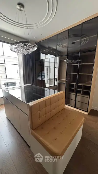 Luxurious modern living room with elegant chandelier and stylish glass cabinetry.