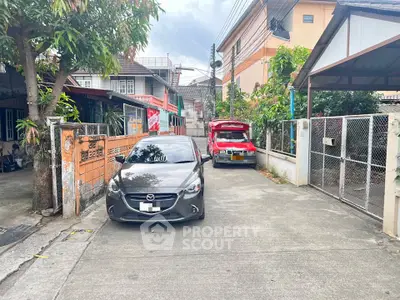 Charming residential street view with parked cars and lush greenery, showcasing a serene neighborhood atmosphere.