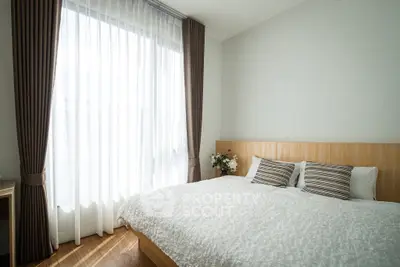 Bright and cozy bedroom with large window and elegant curtains, perfect for relaxation.