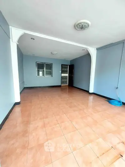 Spacious empty room with tiled flooring and blue walls, ideal for customization.