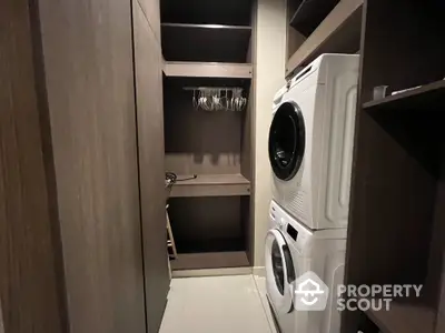 Modern laundry room with stacked washer and dryer in sleek wooden cabinetry.