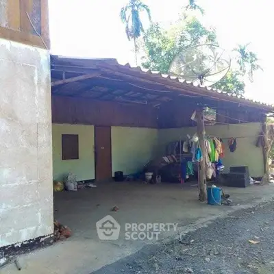 Rustic exterior with covered patio and laundry area, surrounded by lush greenery.