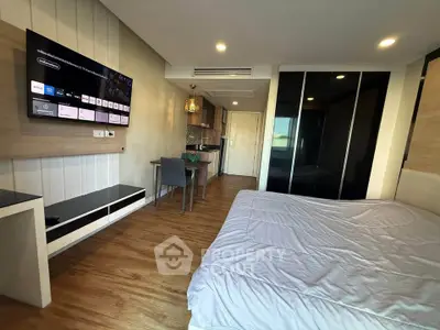 Modern bedroom with sleek design, featuring a wall-mounted TV and stylish kitchenette.