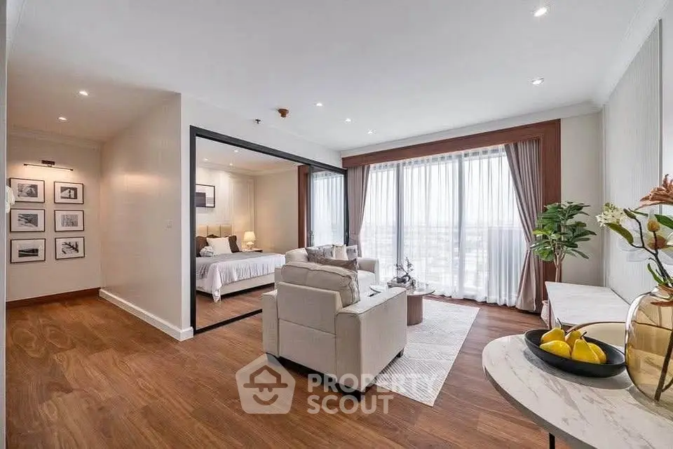 Spacious modern living room with wooden flooring and large windows offering abundant natural light.