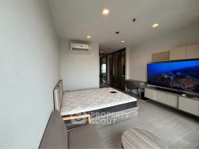 Modern bedroom with sleek design, featuring a large TV and comfortable seating area.
