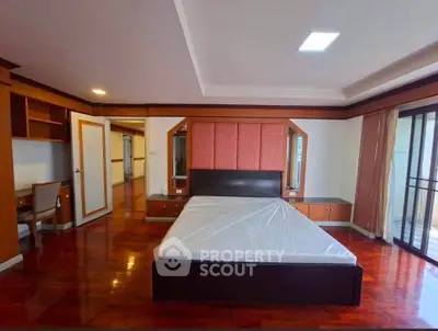 Spacious bedroom with elegant wooden flooring and large windows for natural light.