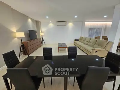 Spacious modern living room with sleek black dining table and cozy beige sofa.
