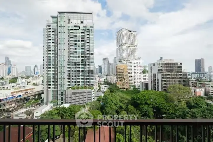 Stunning cityscape view from a high-rise balcony overlooking lush greenery and modern skyscrapers.