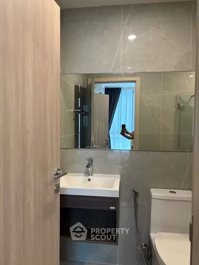Modern bathroom with sleek sink and large mirror in stylish apartment.