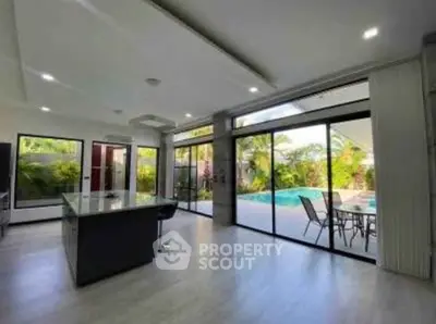 Spacious modern kitchen with pool view and open layout, perfect for entertaining.