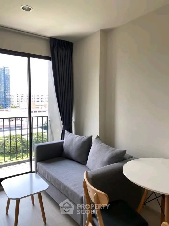 Cozy living room with modern furniture and balcony view in urban apartment.