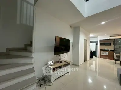 Modern living room with sleek TV setup and open layout, showcasing contemporary design and spaciousness.