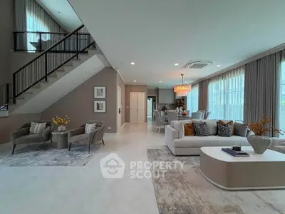 Spacious modern living room with elegant decor and open layout, featuring a cozy seating area and stylish staircase.