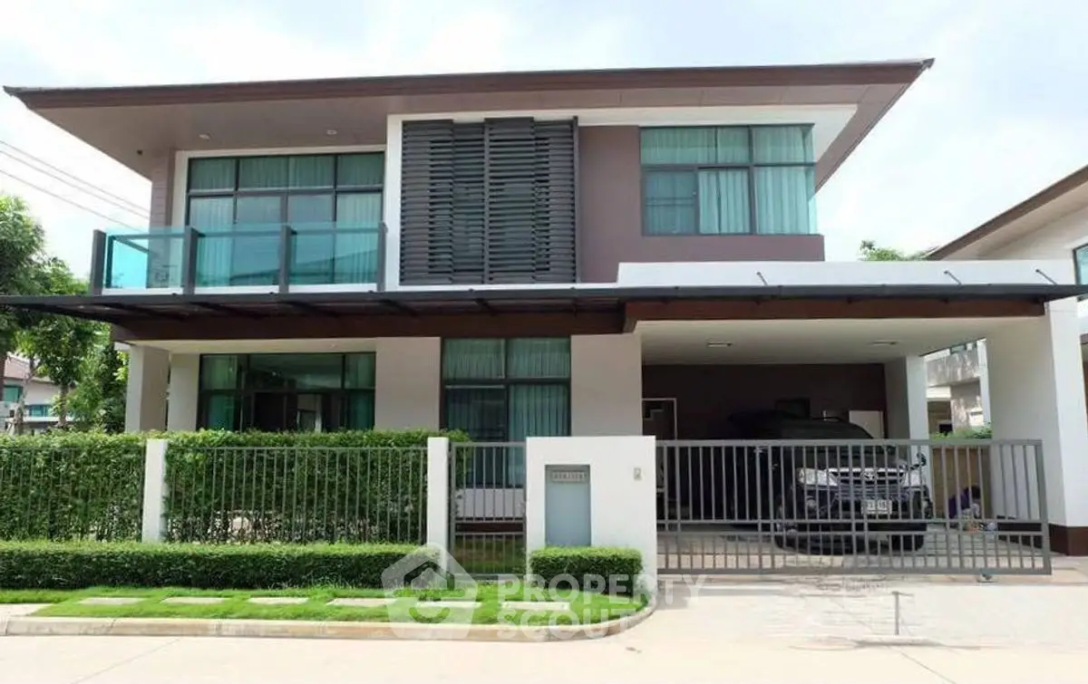 Modern two-story house with large windows and gated driveway in suburban neighborhood.