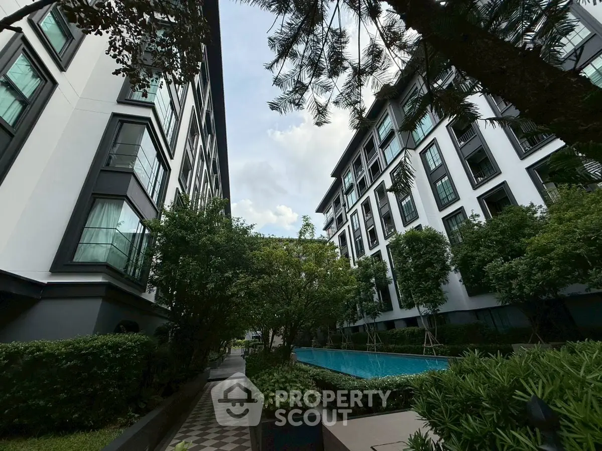Modern apartment complex with lush greenery and swimming pool