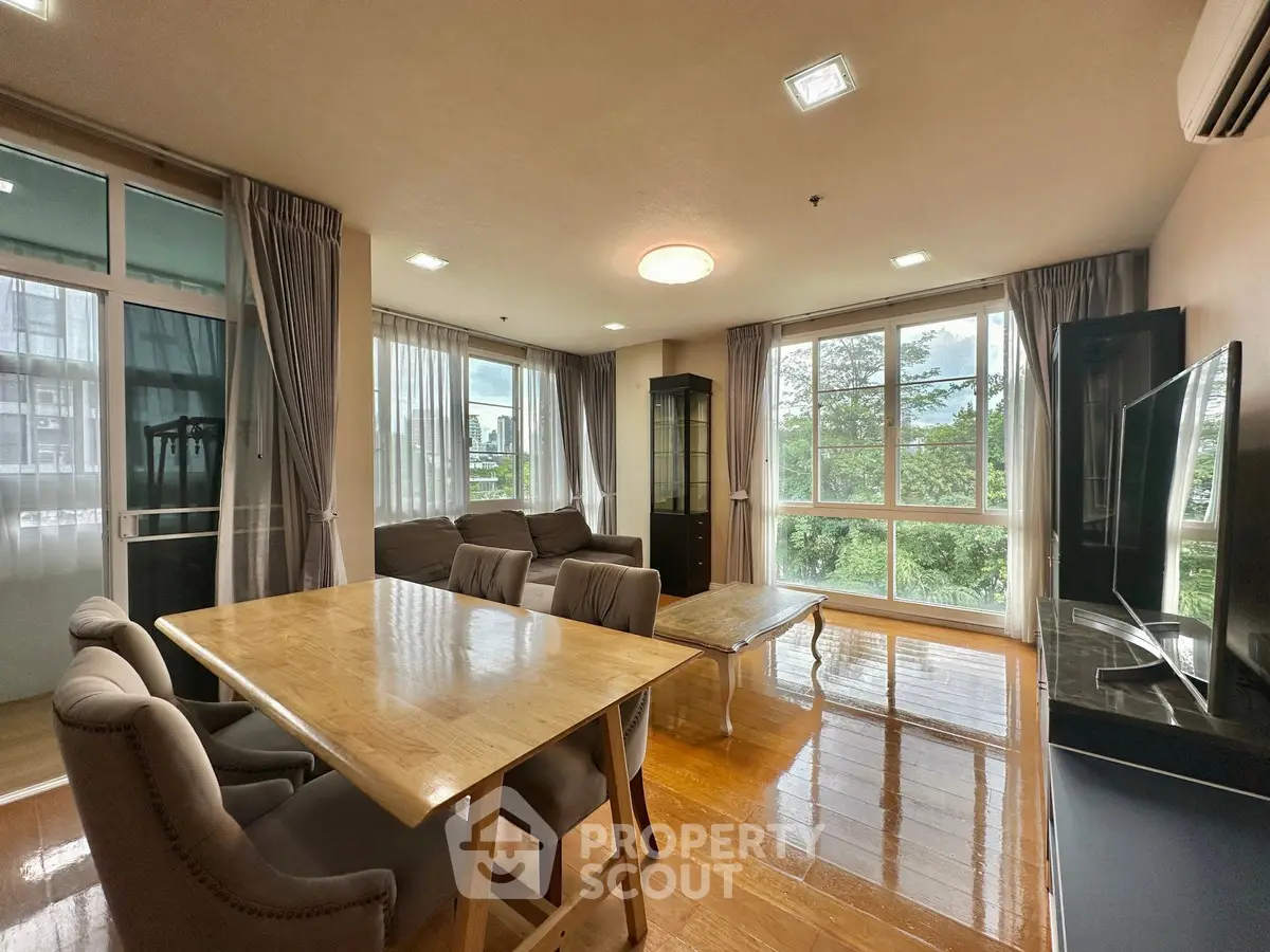 Spacious living room with large windows and elegant dining area