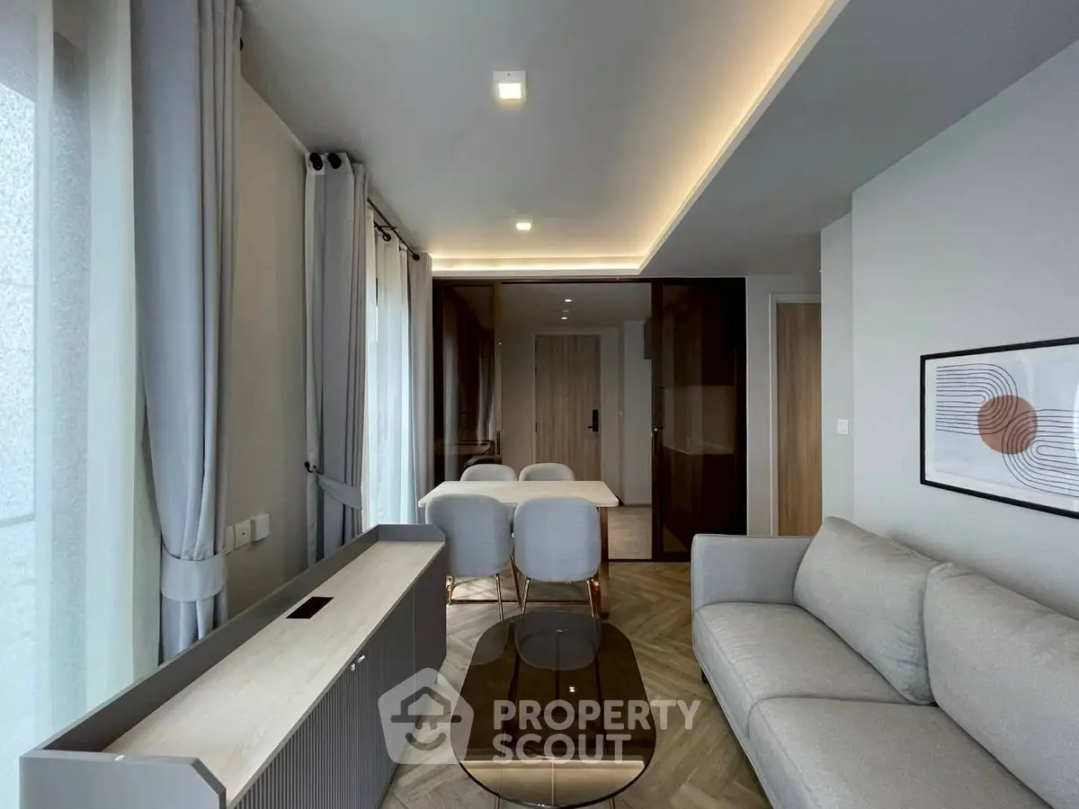Modern living room with stylish furniture and elegant lighting, featuring a cozy sofa and a sleek dining area.
