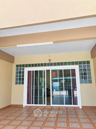 Spacious covered patio with sliding glass doors and decorative tile flooring.