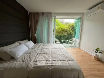 Modern bedroom with balcony and lush garden view, featuring cozy bedding and elegant decor.