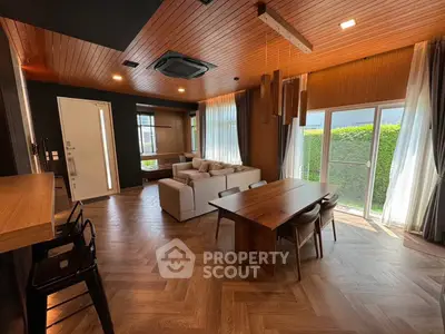 Luxurious modern living room with wooden accents and large windows opening to a lush garden view.