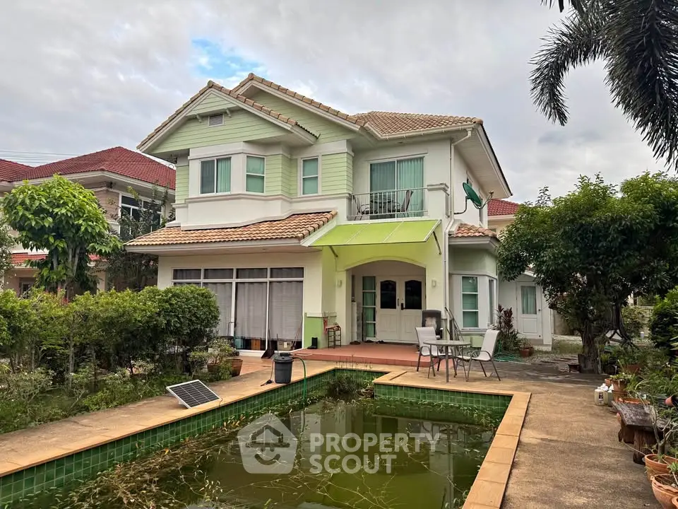 Charming two-story house with lush garden and serene pond, perfect for family living.